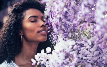 Thoughtful happy young black woman surrounded by flowers